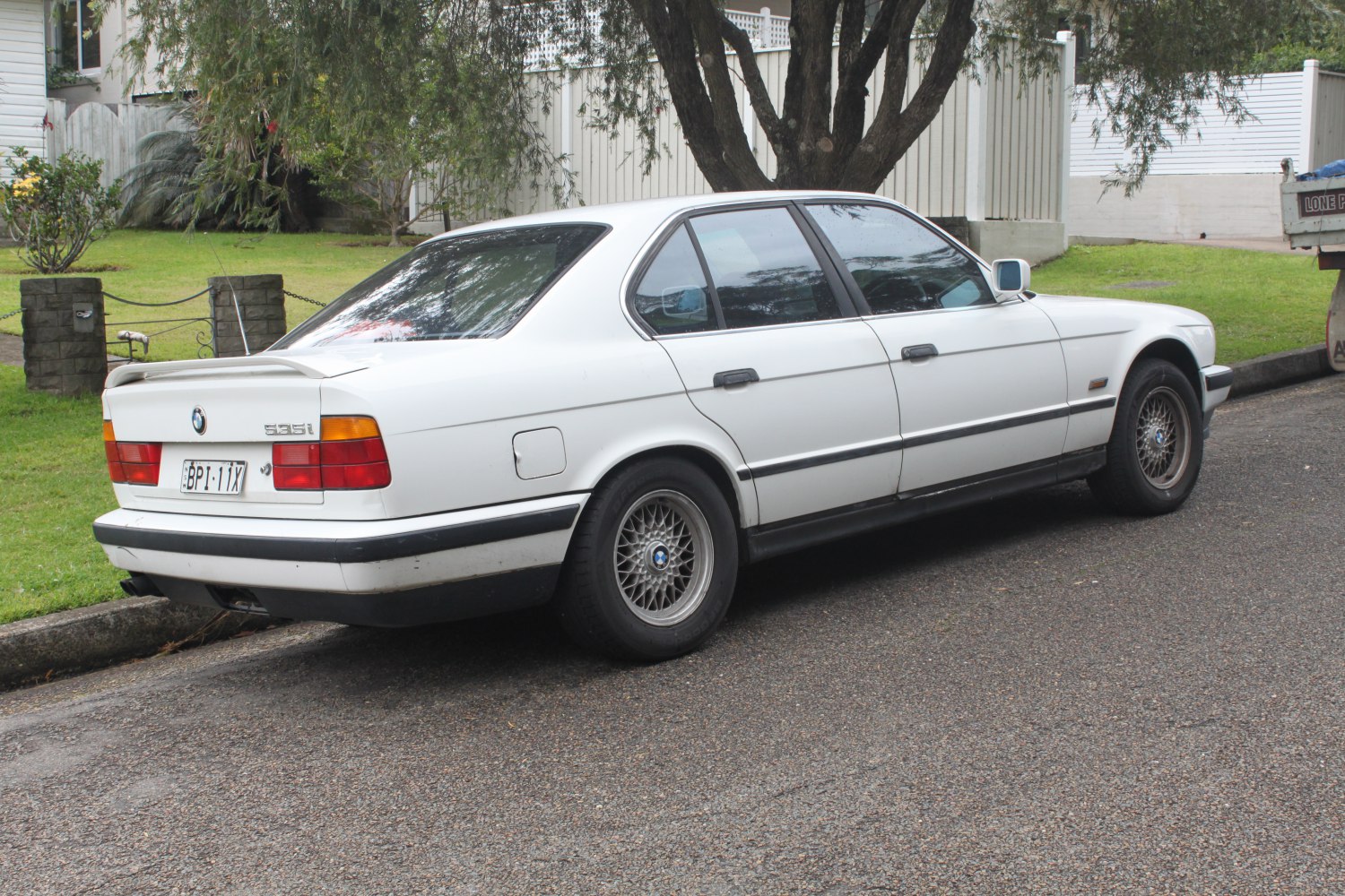 Rear side view of a vintage sedan with alloy wheels and rear spoiler