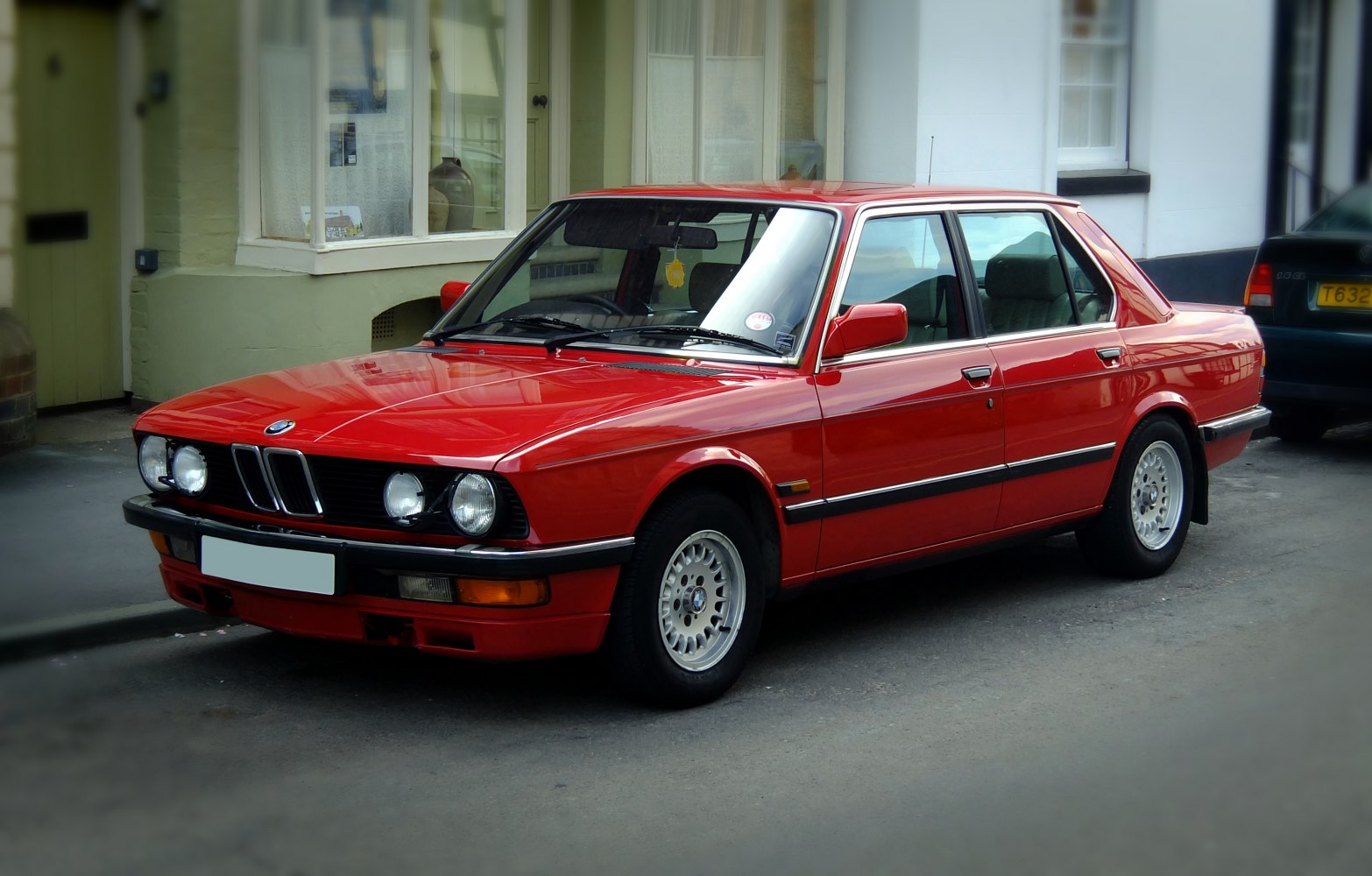 Red sedan with quad round headlights and alloy wheels