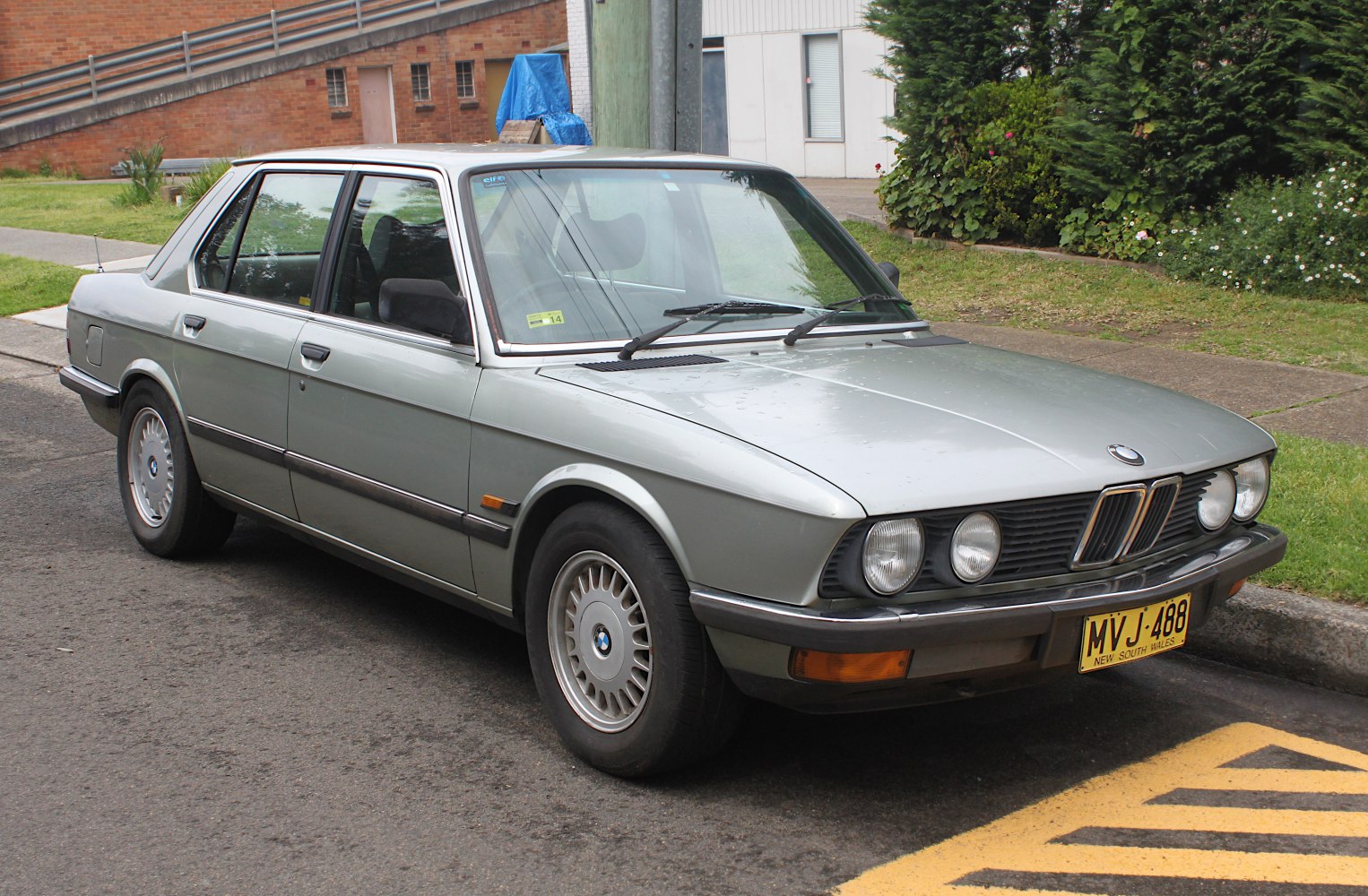 Classic sedan front side view with quad round headlights and alloy wheels.