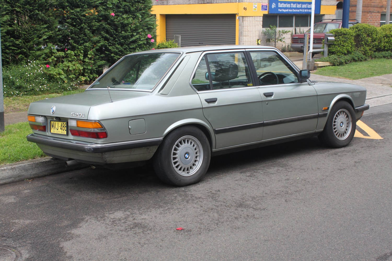 Rear side view of a vintage mid-80s sedan with alloy wheels and classic taillights