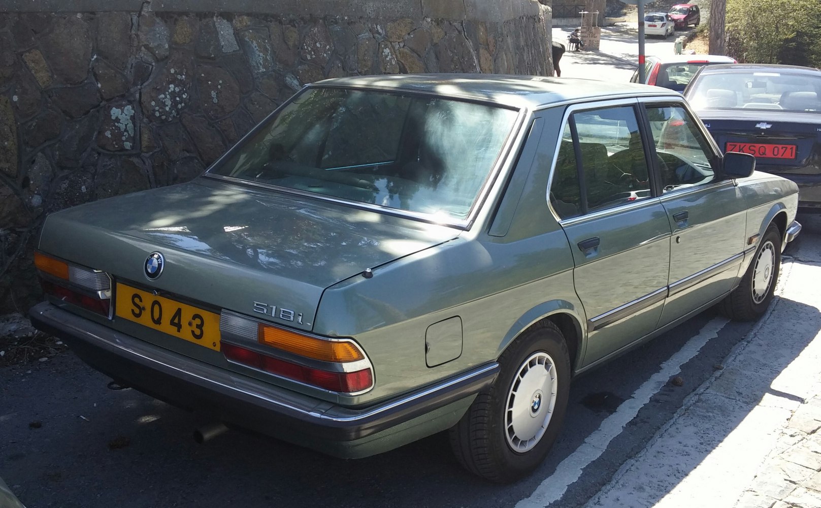 Rear and side view of a vintage four-door sedan with distinct 1980s design cues
