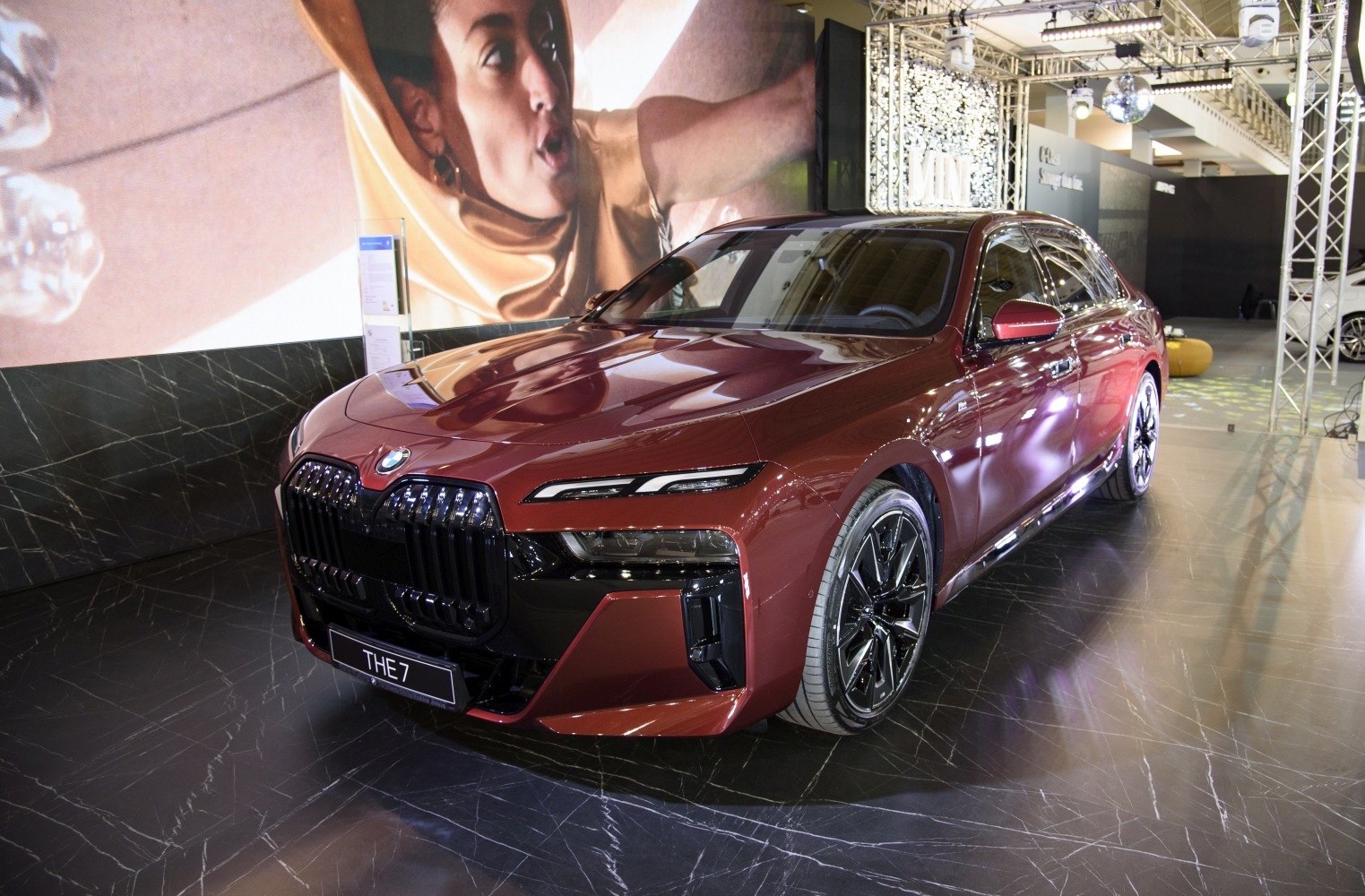 Luxury sedan with large grille and sharp LED headlights in showroom