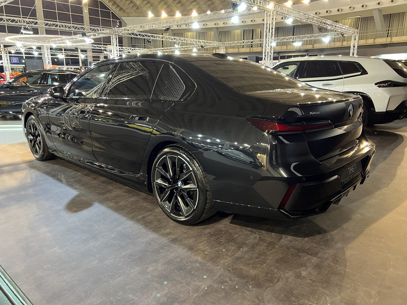 Black luxury sedan rear and side with glossy black alloy wheels