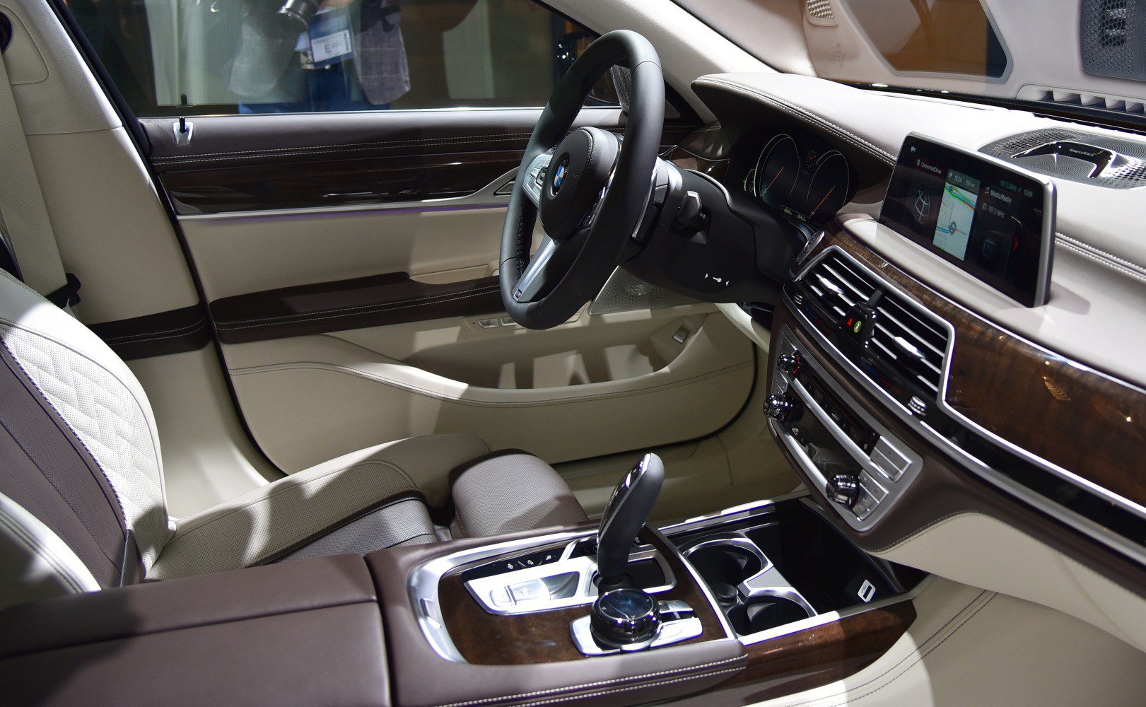Luxury car interior with leather seats, wood trim, and digital infotainment system.