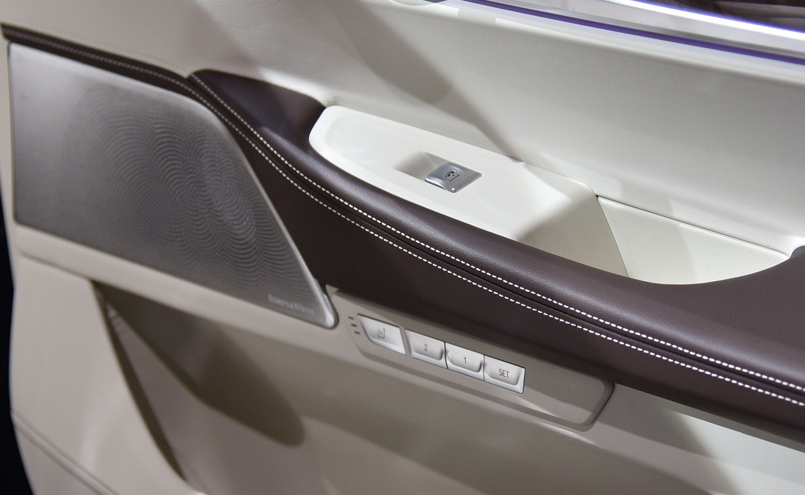 Luxury car door interior with leather, controls, and speaker