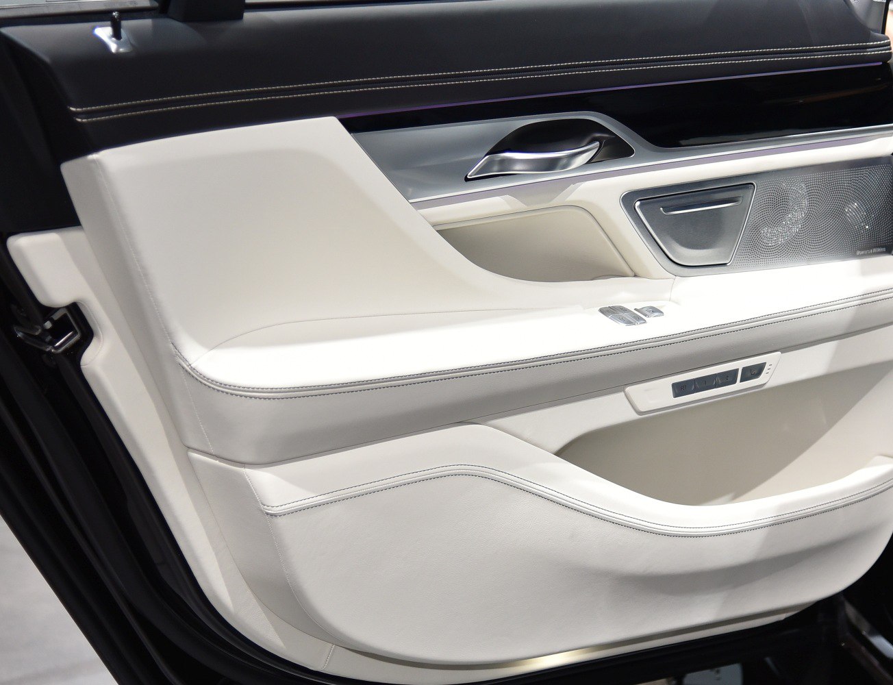 White leather interior door panel with control buttons and speaker