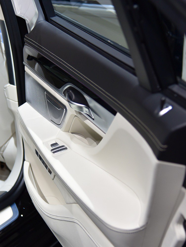 Luxury interior door panel with leather, metal handle, and control buttons