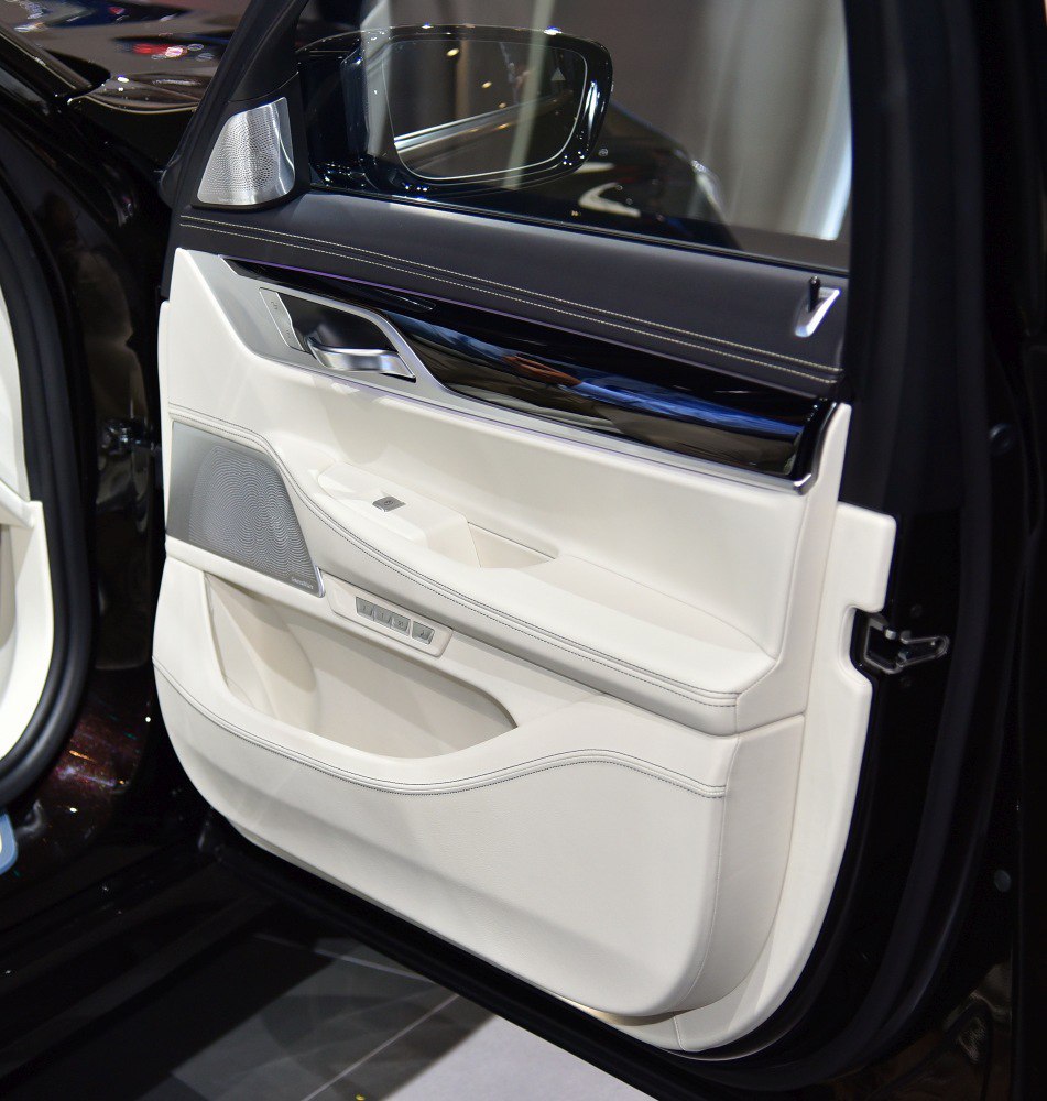 Luxury black and white stitched leather interior door panel with speaker and controls.