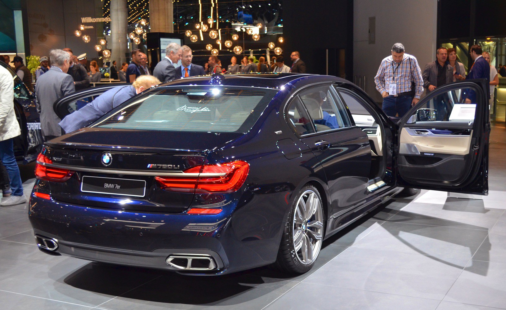 Rear and side view of luxury sedan with open rear door and taillights