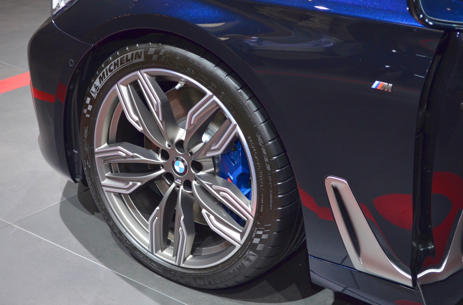 Close-up of alloy wheel and blue brake caliper on luxury sedan.