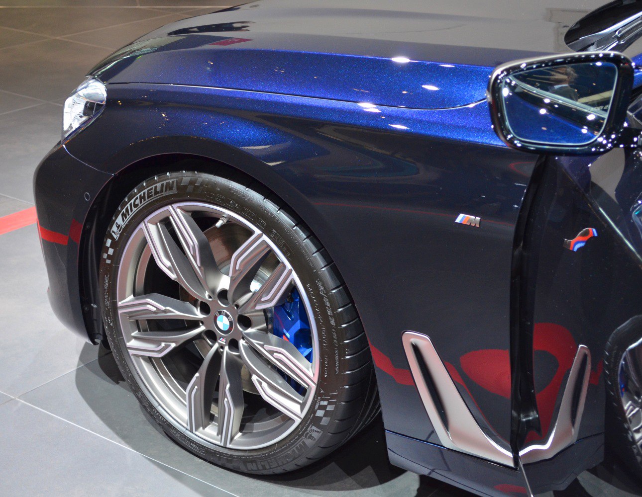 Wheel with Michelin tire, blue brake caliper, and side vent on vehicle front fender