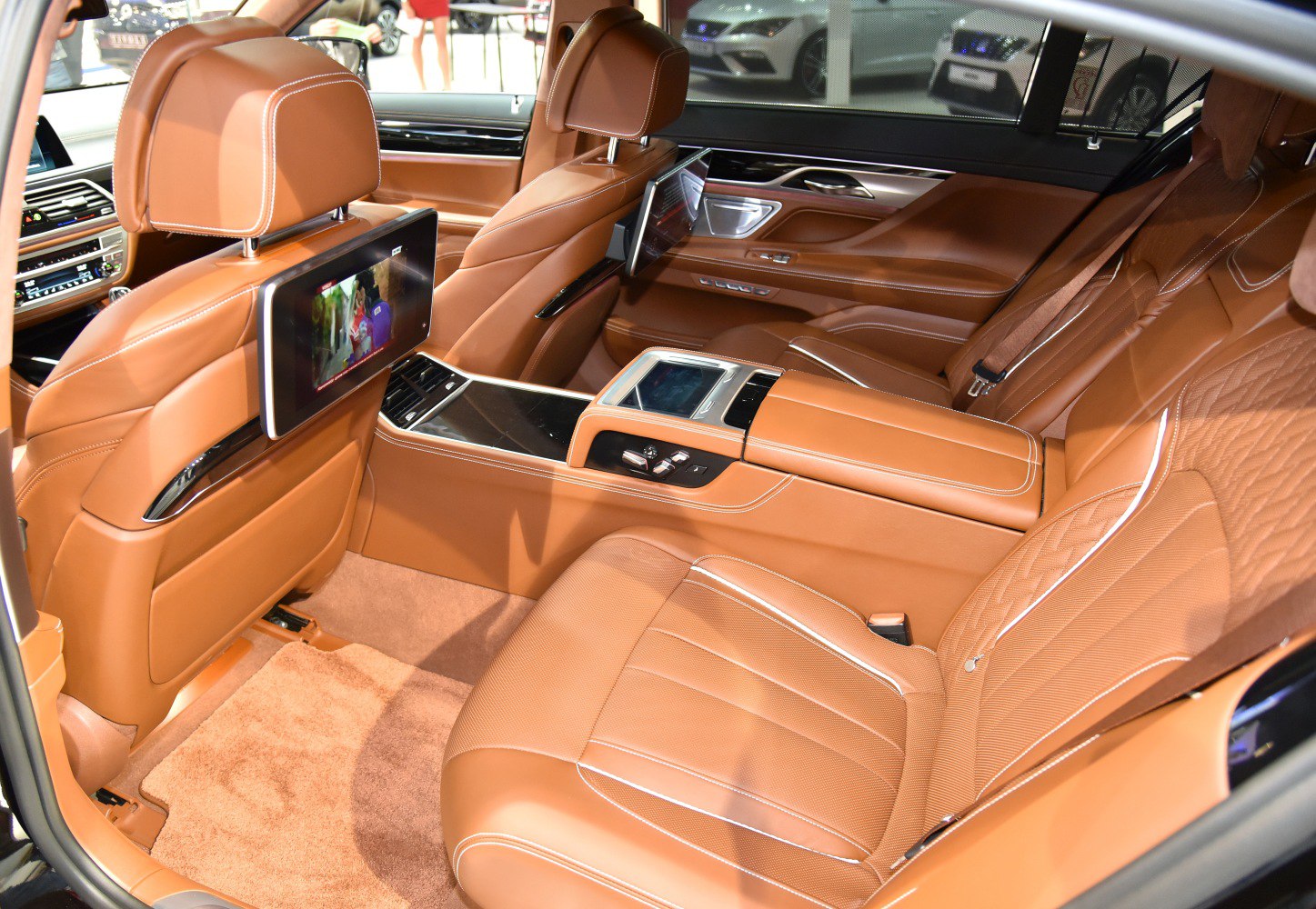 Brown leather rear seats with dual entertainment screens and central touchscreen controls