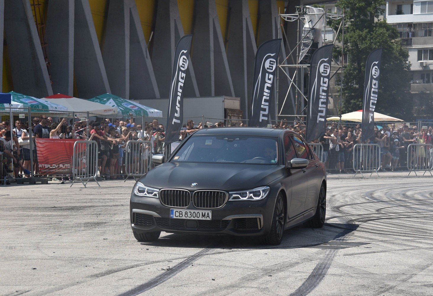 Matte black luxury sedan front with LED headlights and tire marks
