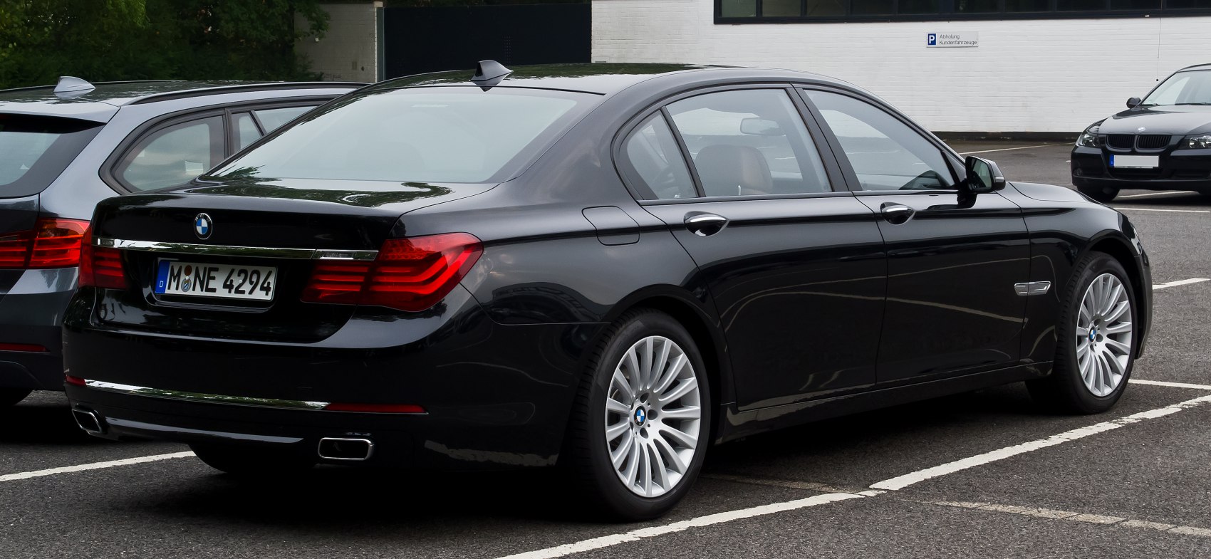 Luxury sedan rear with dual rectangular exhaust and multi-spoke alloy wheels