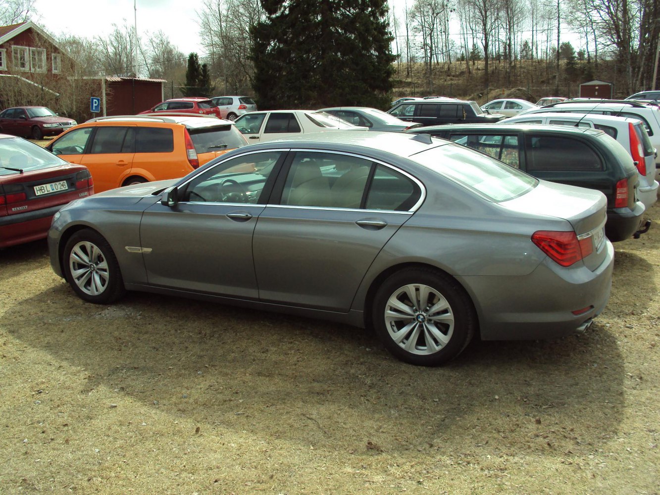Side profile of a luxury silver sedan with alloy wheels parked on grass