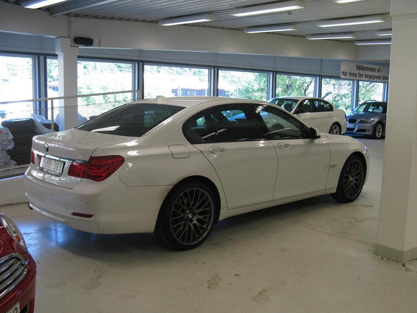 White luxury sedan rear side with distinctive tail lights and multi-spoke wheels