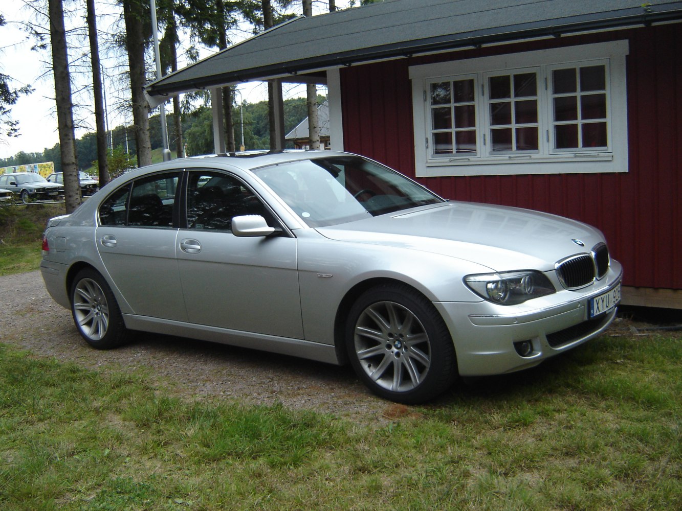 Front side view of a silver luxury sedan with alloy wheels parked on grass.