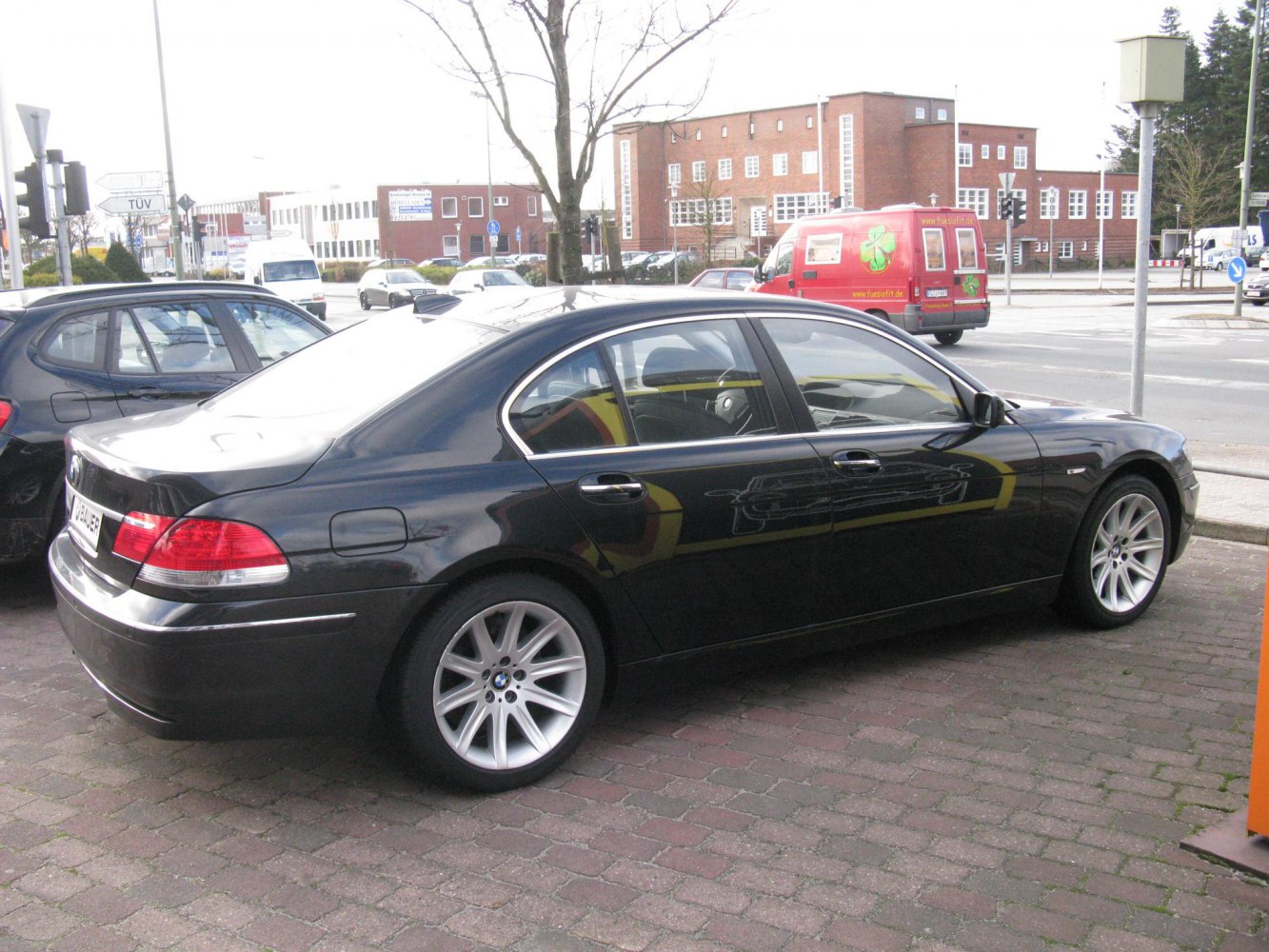 Rear-side view of luxury sedan with alloy wheels and sleek black finish.