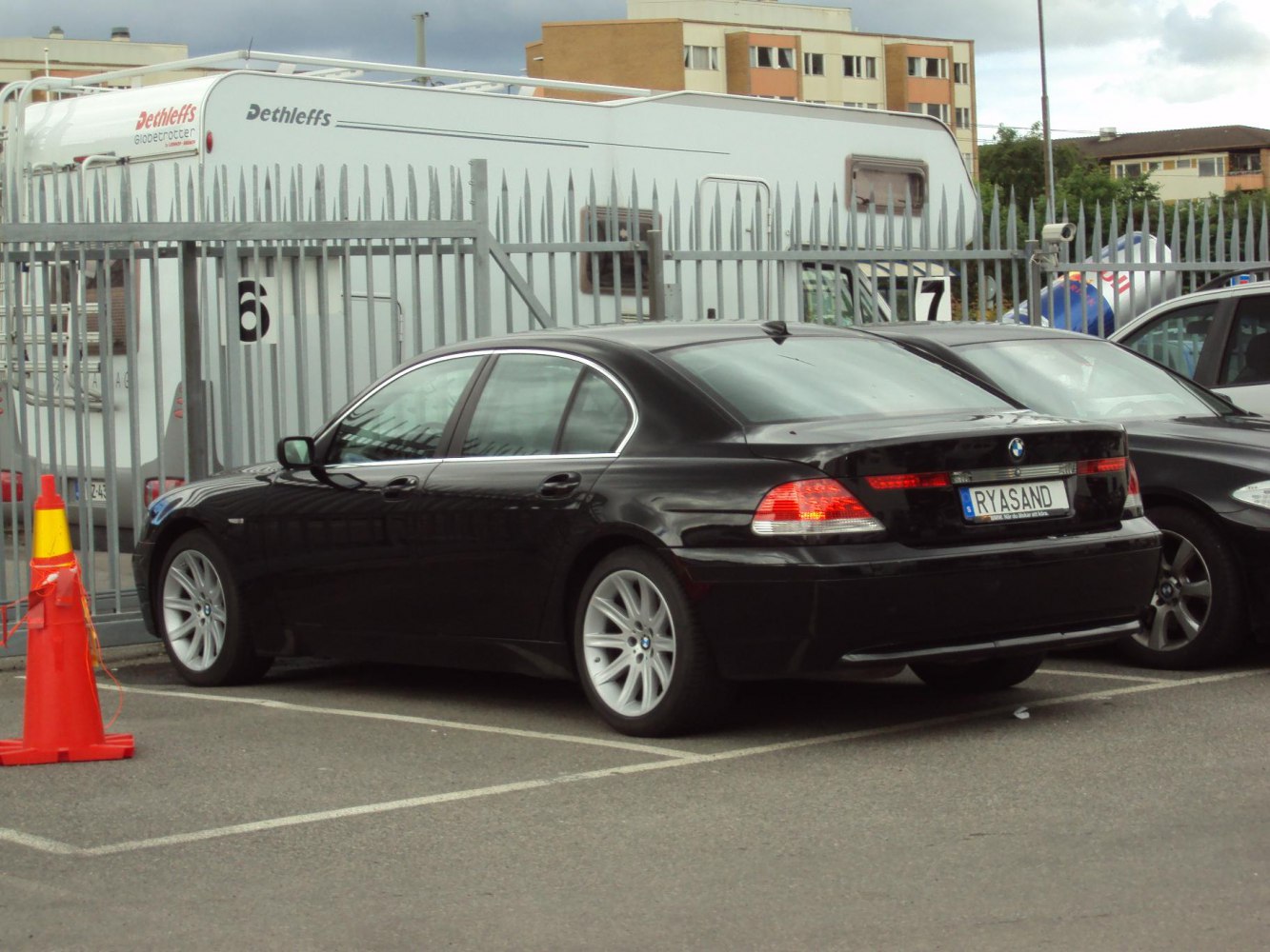 Luxury black sedan rear side view with alloy wheels and tinted windows.
