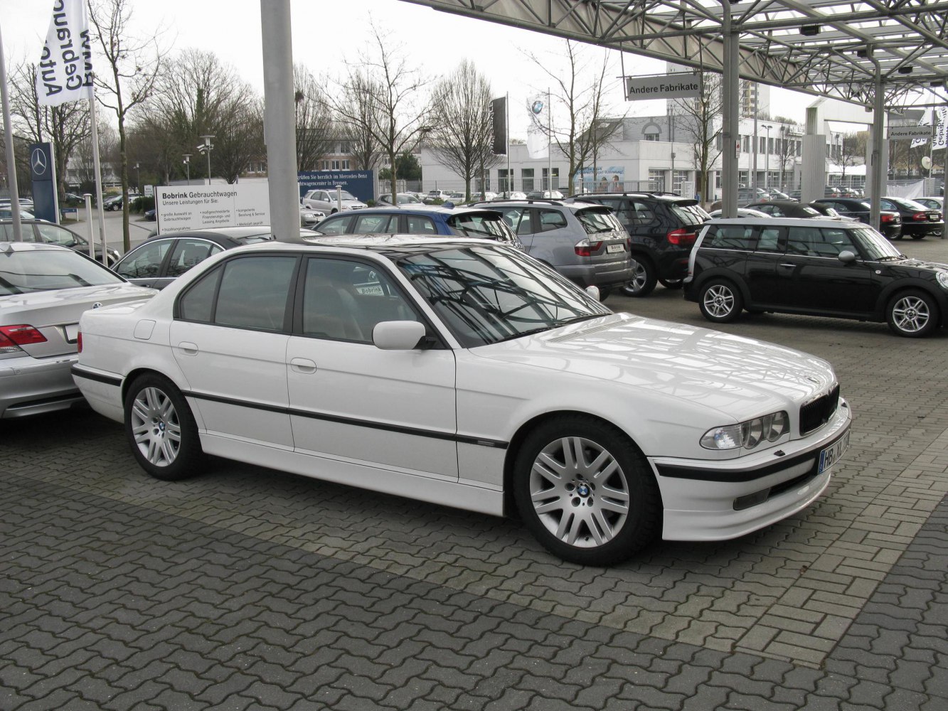 Side view of a white luxury sedan with multi-spoke alloy wheels.