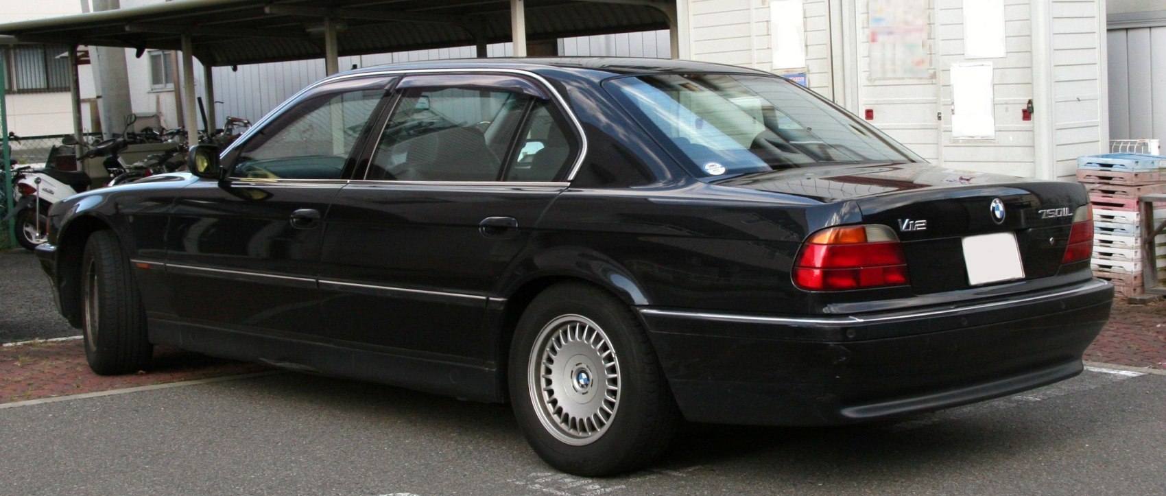 Rear view of luxury sedan with V12 badge and multi-spoke alloy wheels
