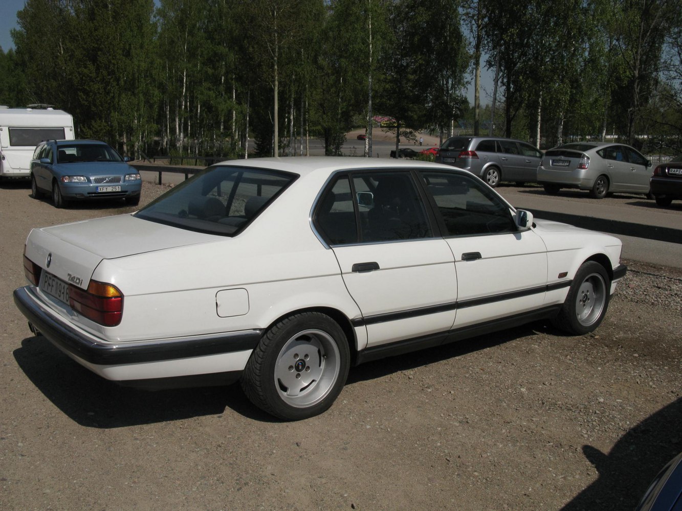 Classic sedan rear side with alloy wheels on gravel lot
