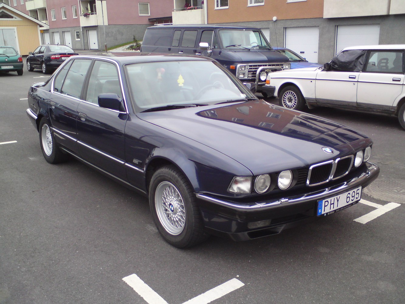 Front-side view of a 1992 luxury sedan with quad round headlights and classic alloy wheels