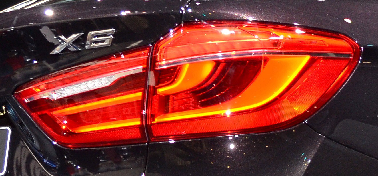 Close-up of rear tail light and X6 badge on black vehicle.