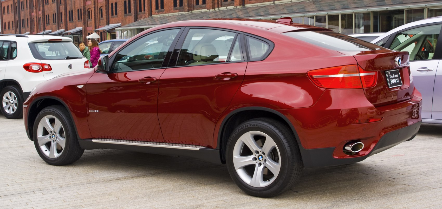 Side rear view of red SUV with coupe roofline and alloy wheels