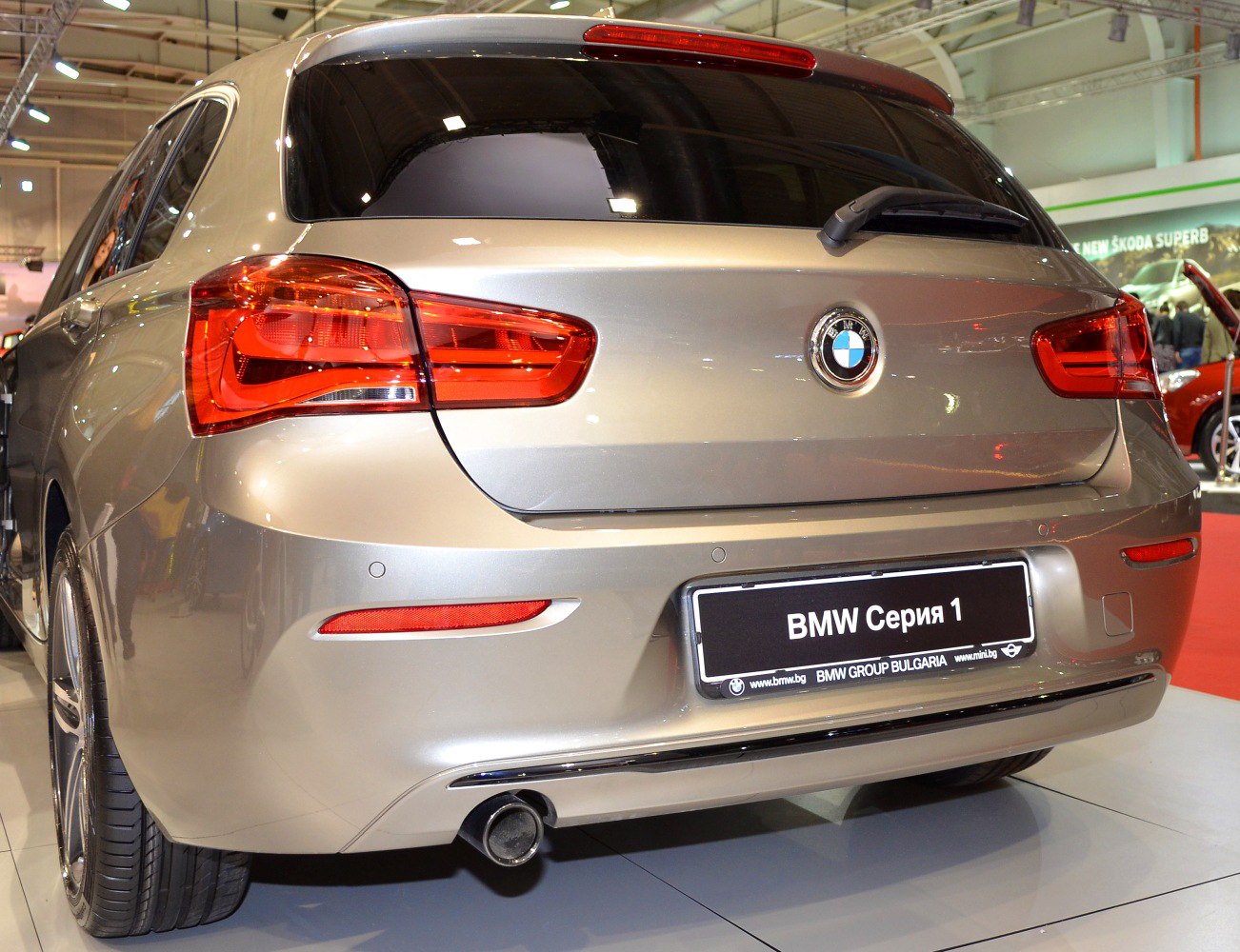 Rear hatchback view with taillights, single exhaust, and parking sensors.