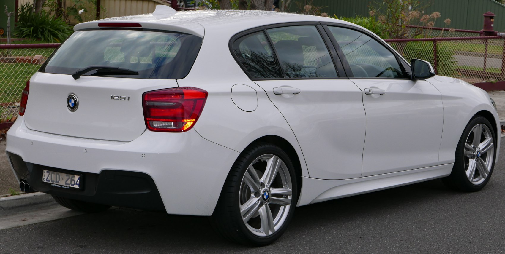 Rear view of white 5-door hatchback showing taillights, alloy wheels, and rear wiper.