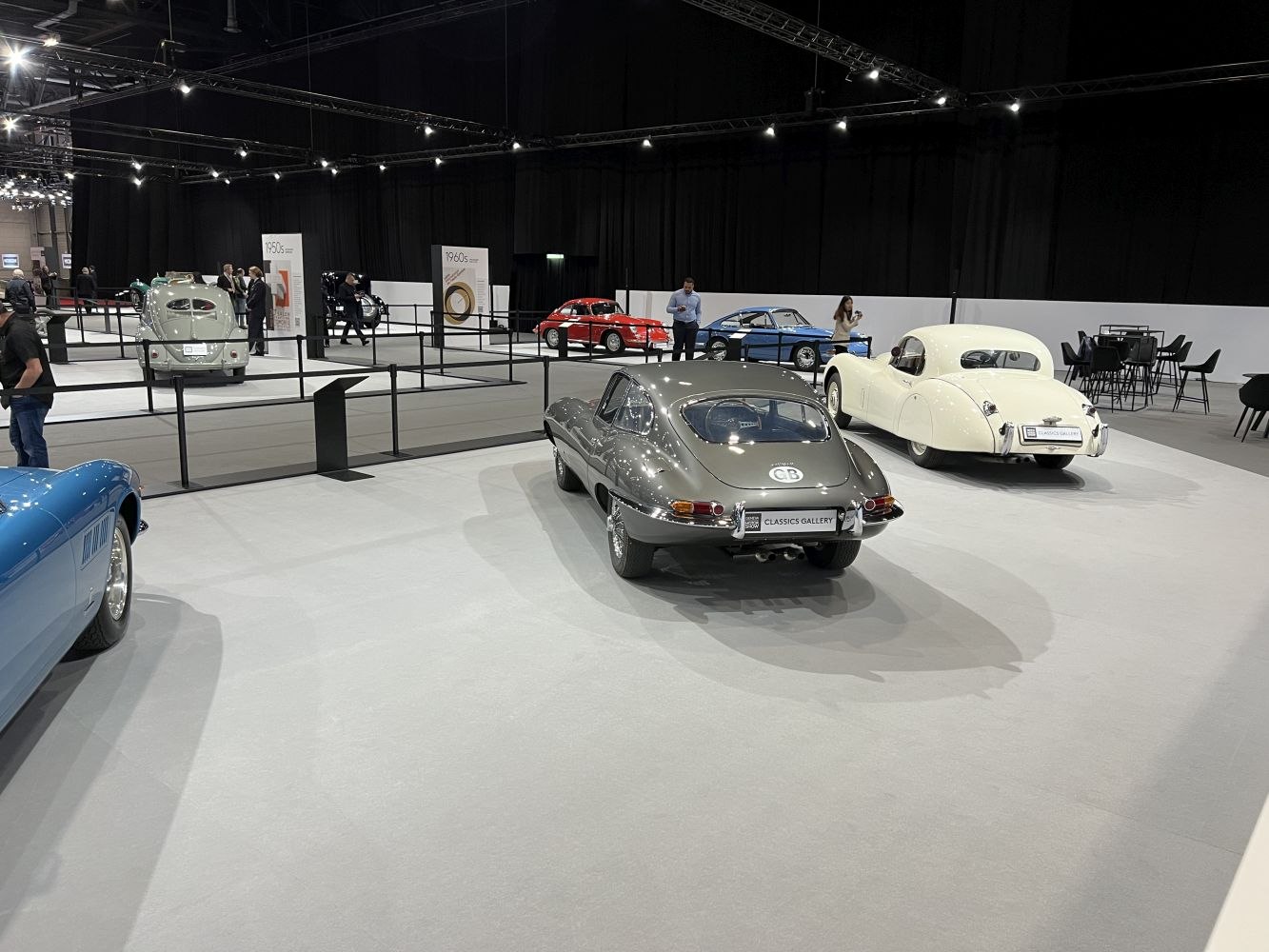 Rear view of a sleek Jaguar E-type with round taillights and chrome bumpers at a car exhibition