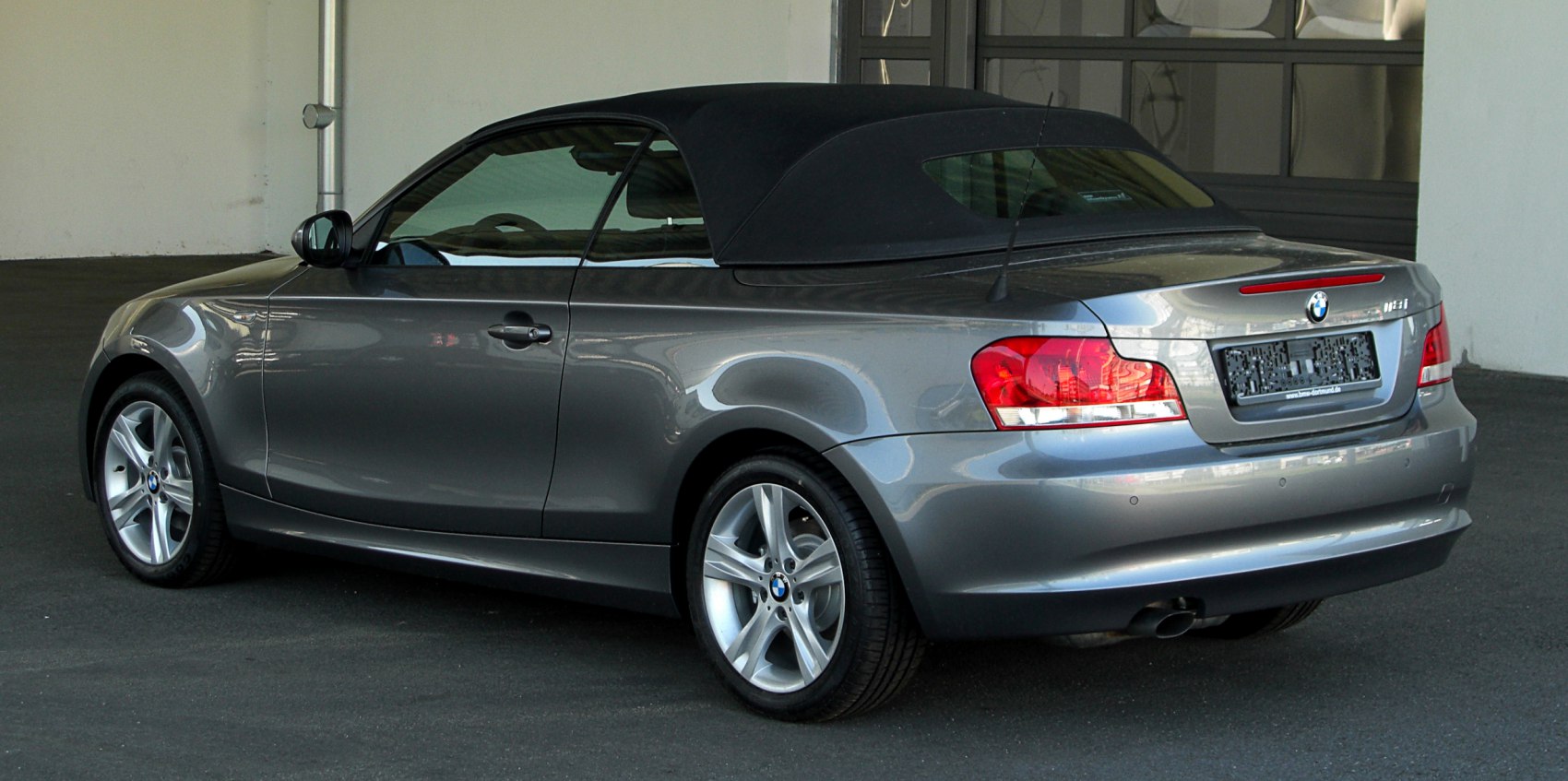 Convertible with closed soft top and alloy wheels rear side view