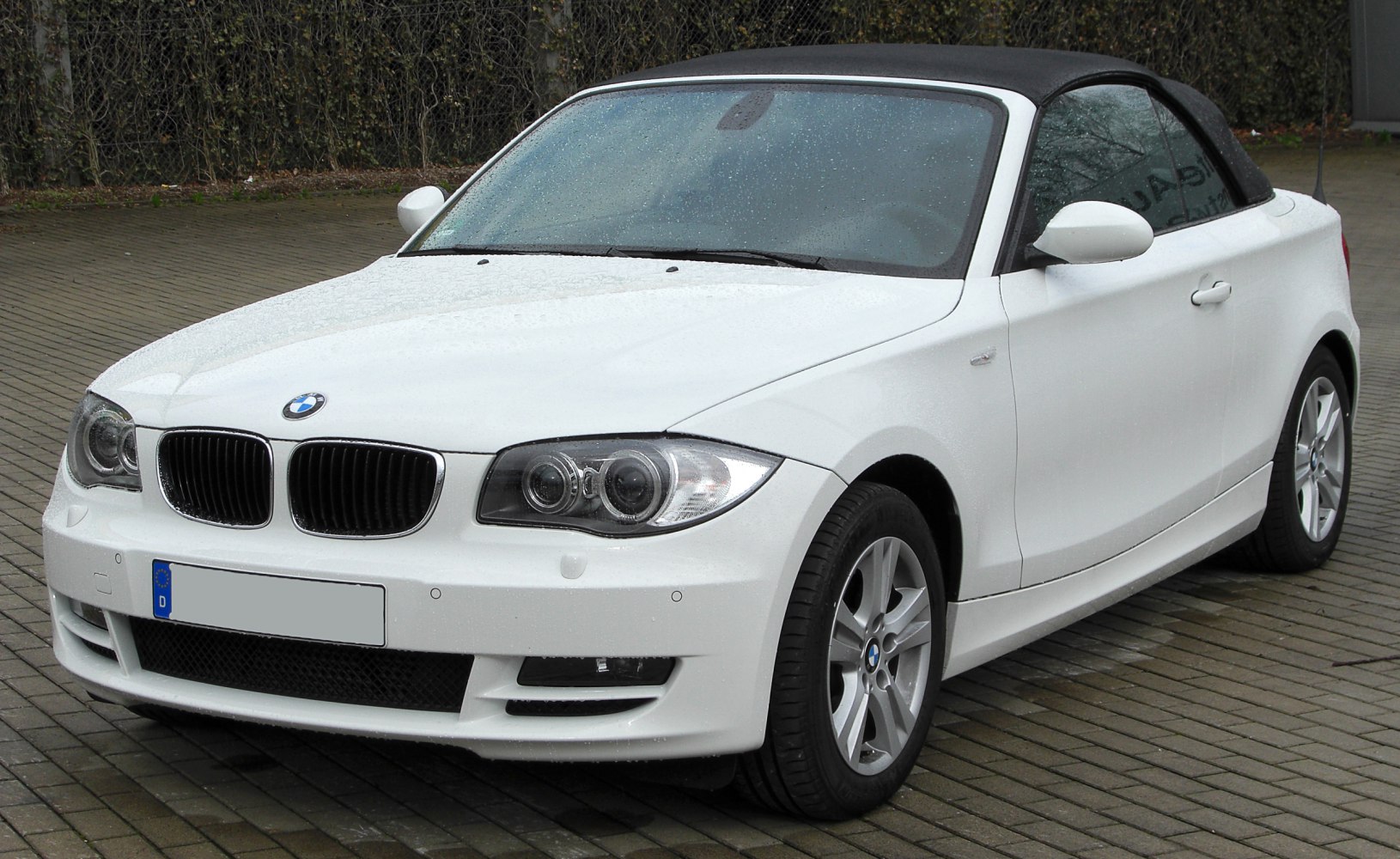 Front view of a white convertible with closed soft roof and distinctive headlights.