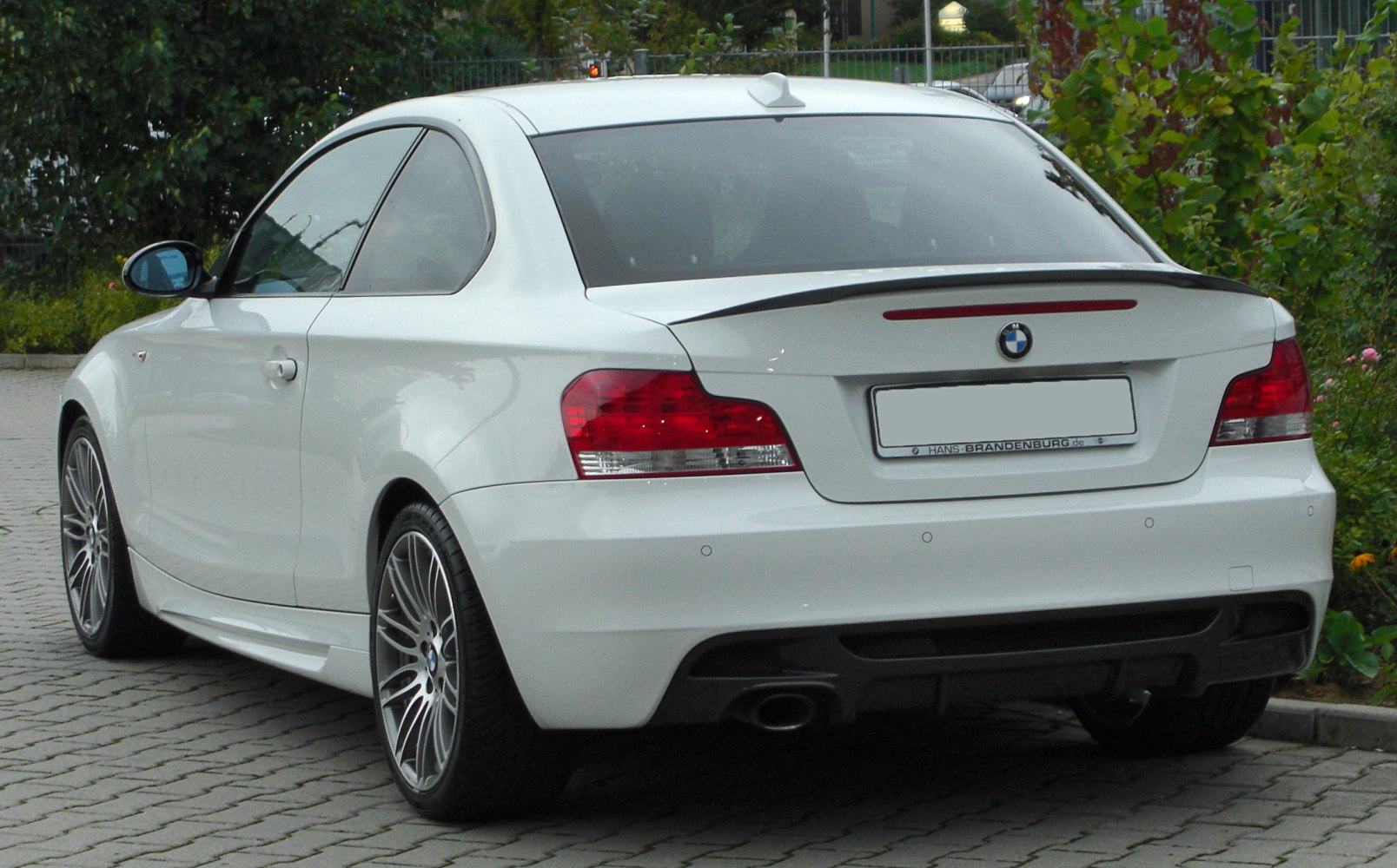 Rear-side view with tail lights and spoiler of white coupe