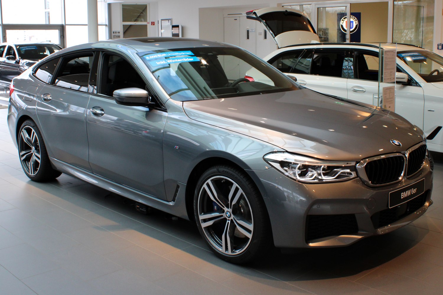 Front side view of a metallic luxury sedan with distinct LED headlights and sporty alloy wheels.