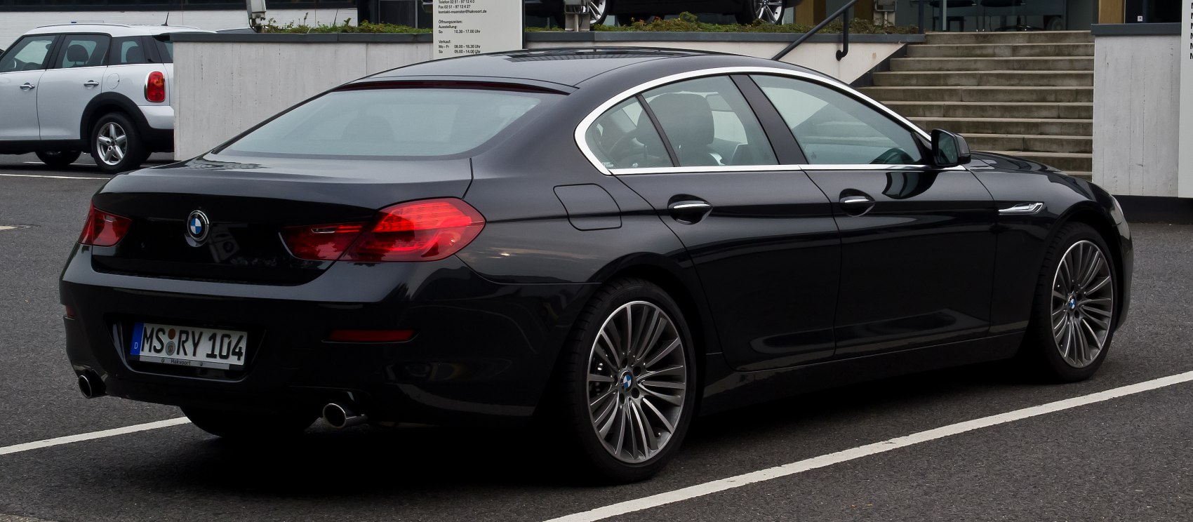 Rear-side view of a luxury four-door coupe with dual exhaust and alloy wheels.