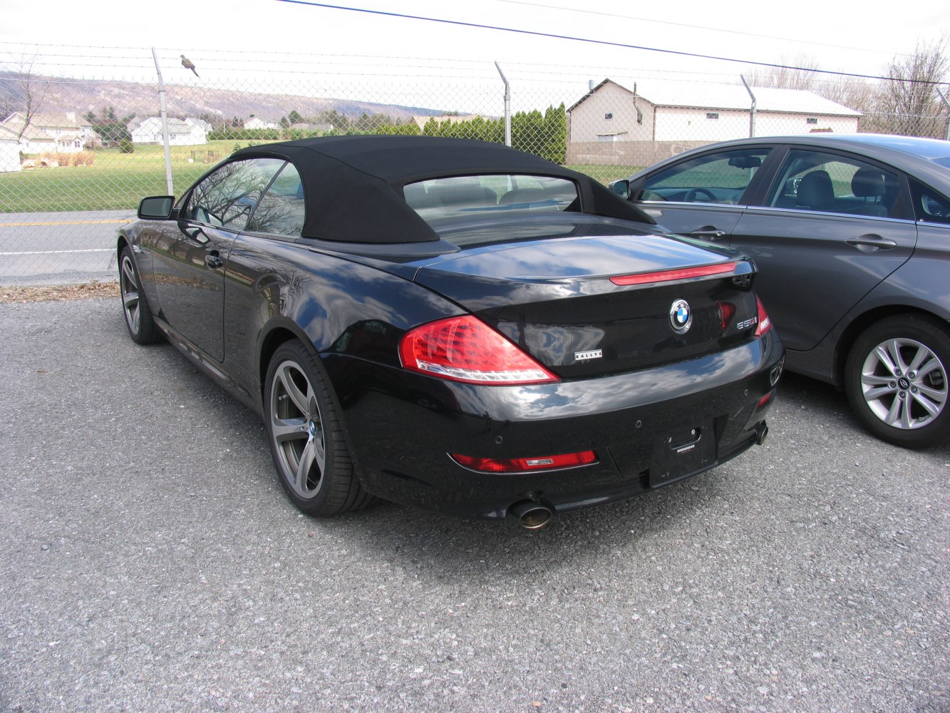 Rear view of black convertible with soft top and dual exhaust