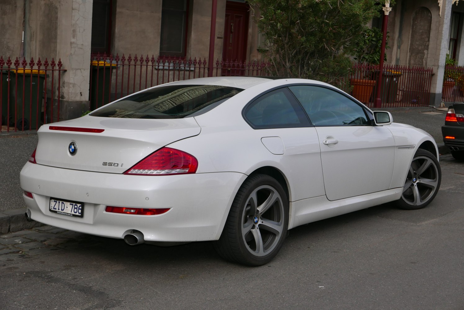 Rear three-quarter view of coupe with distinctive tail lights and twin exhaust