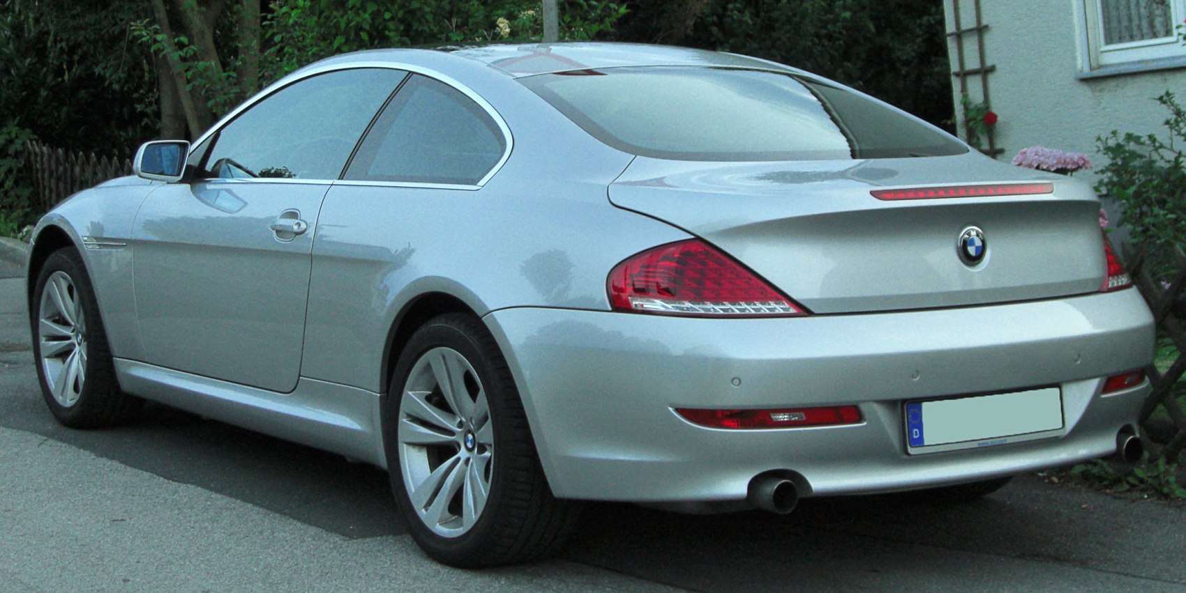 Rear side view of a silver two-door coupe with aerodynamic design and distinctive tail lights.