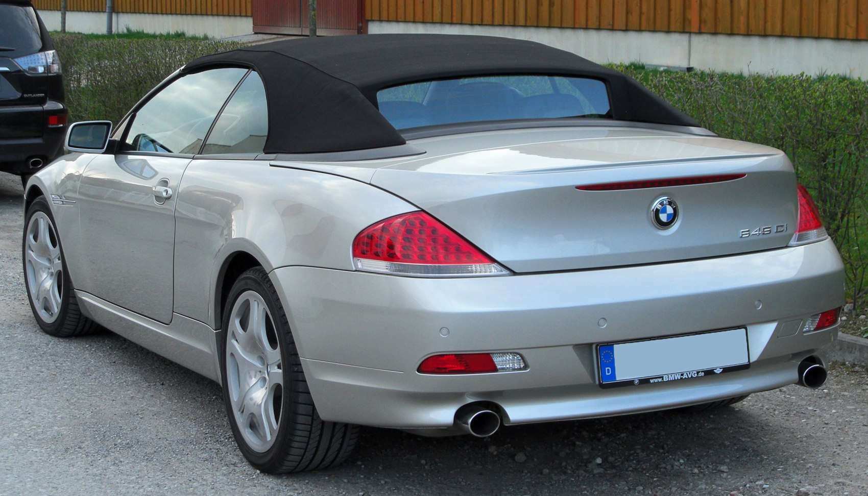 Rear view of a silver convertible with soft fabric roof and dual exhaust