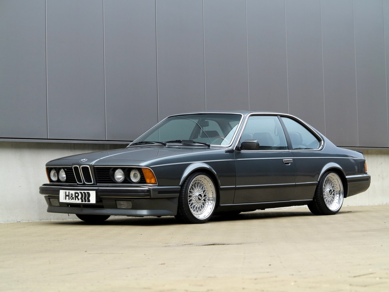 Low-slung vintage coupe with mesh alloy wheels and streamlined body.
