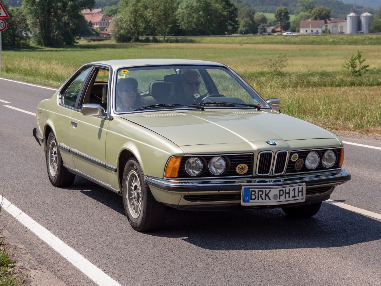 Vintage coupe with quad round headlights and chrome grille on country road