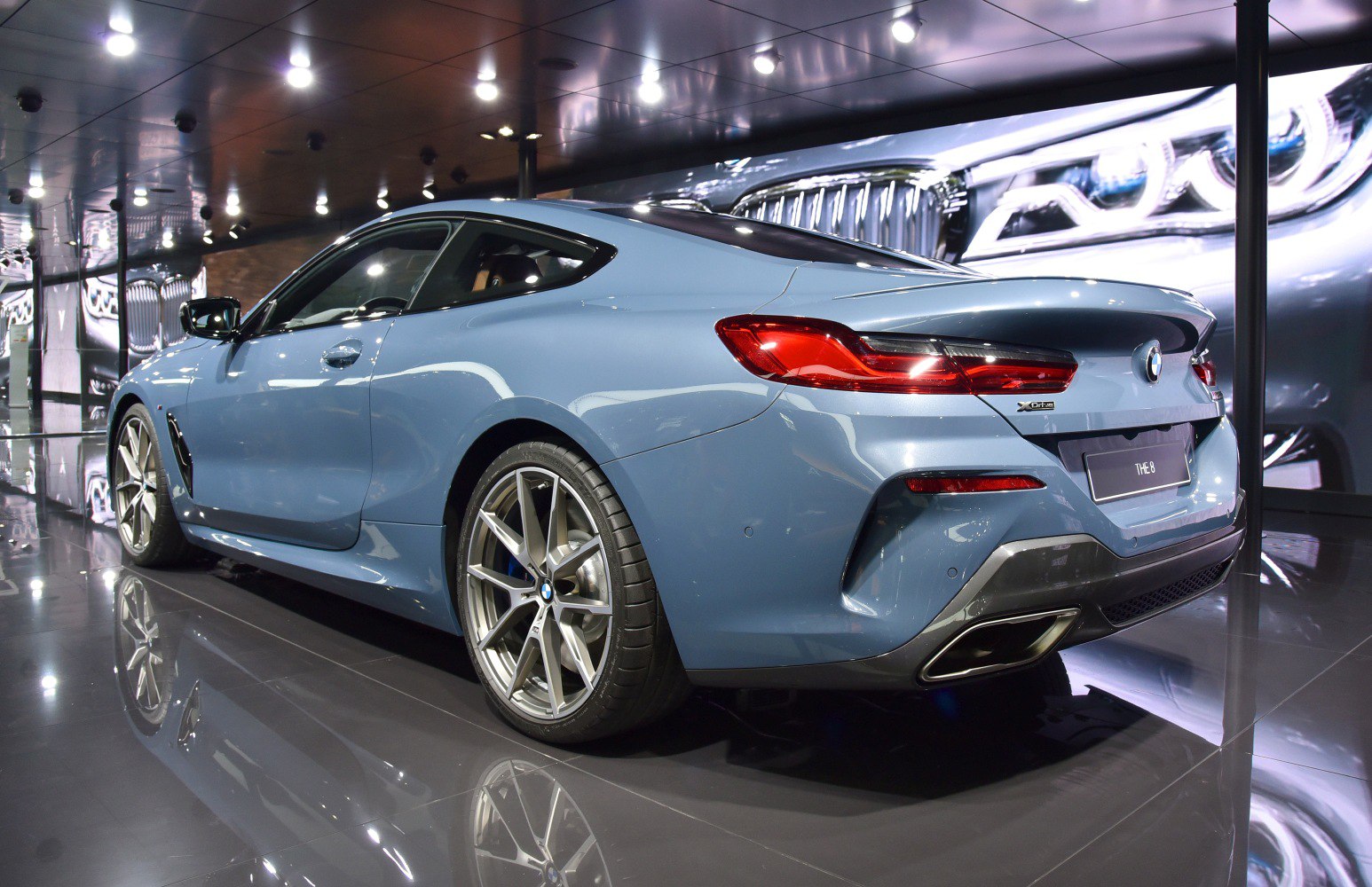 Rear-side view of a sporty blue coupe with dual exhausts and alloy wheels