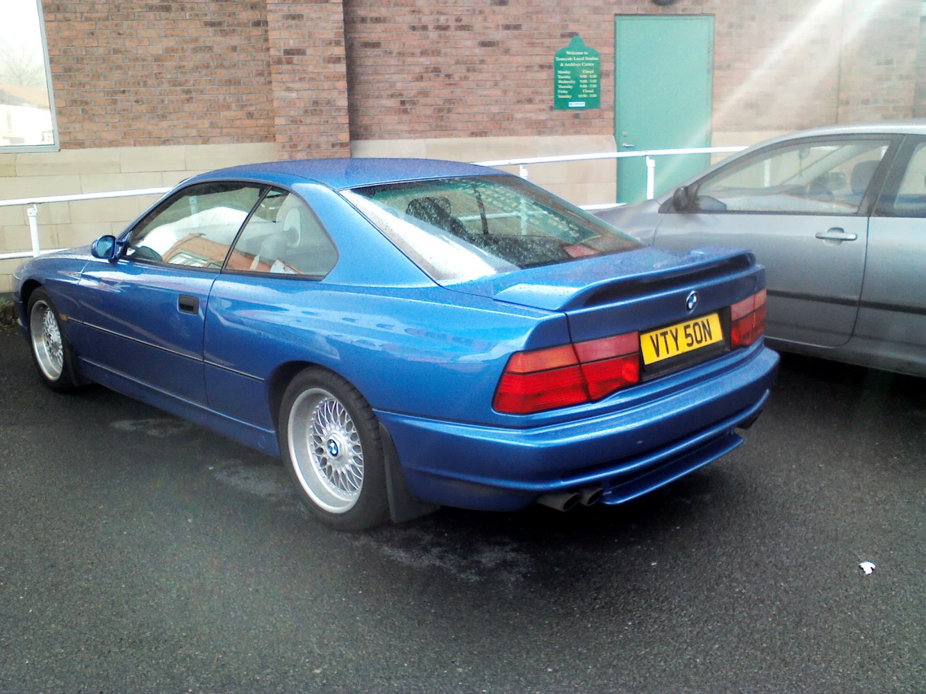 Rear and side view of a blue classic coupe with distinctive taillights and alloy wheels.
