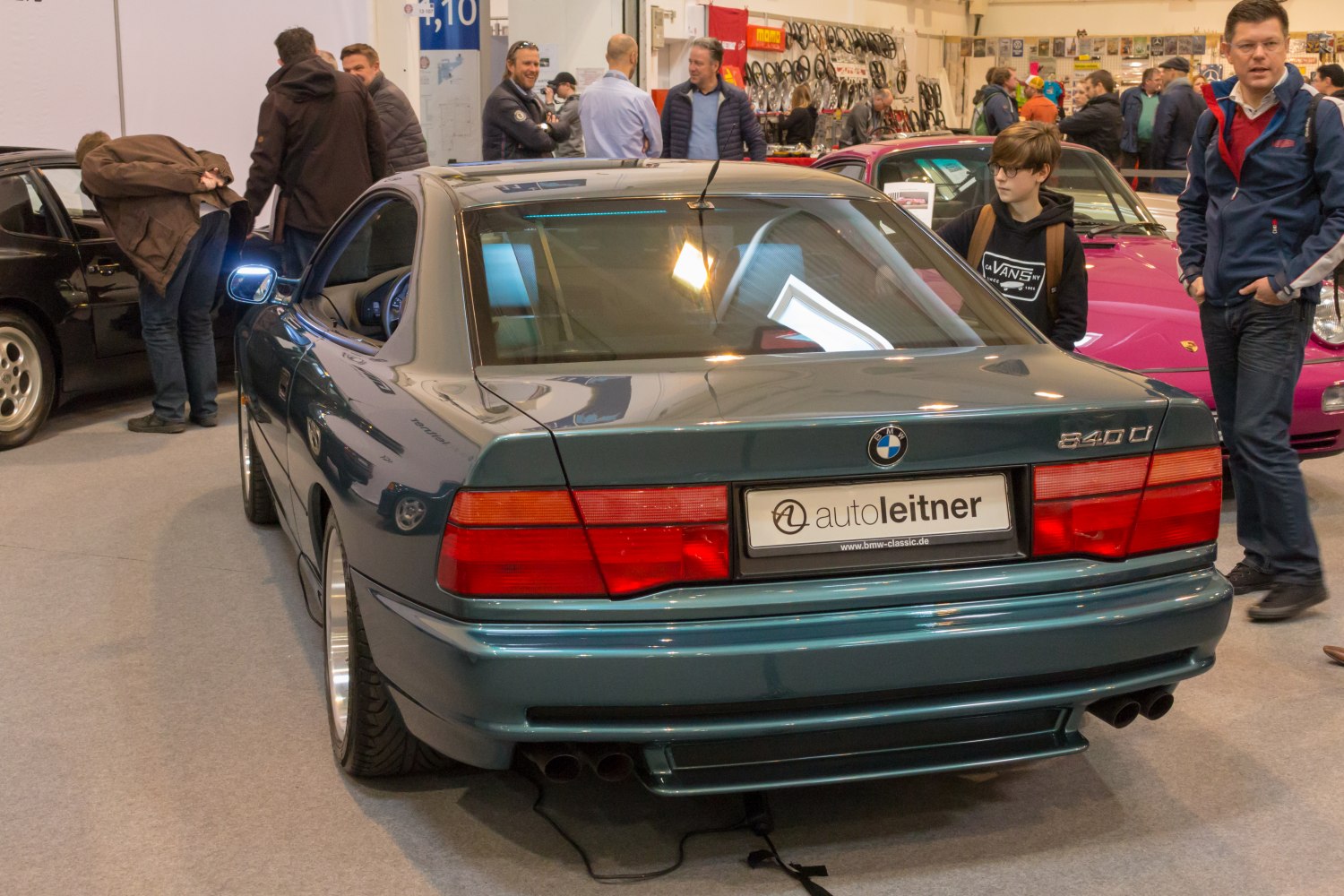 Rear view of a sleek coupe with wide taillights and dual exhaust in showroom