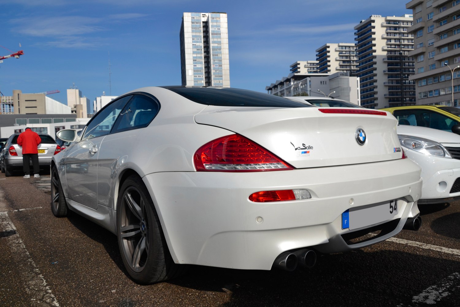 Rear view of white luxury coupe with distinctive taillights and dual exhaust pipes.