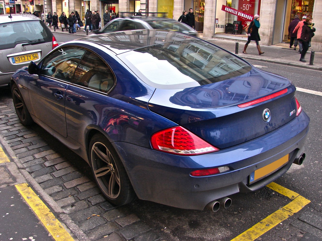 Rear and side view of blue coupe with quad exhaust and sporty wheels