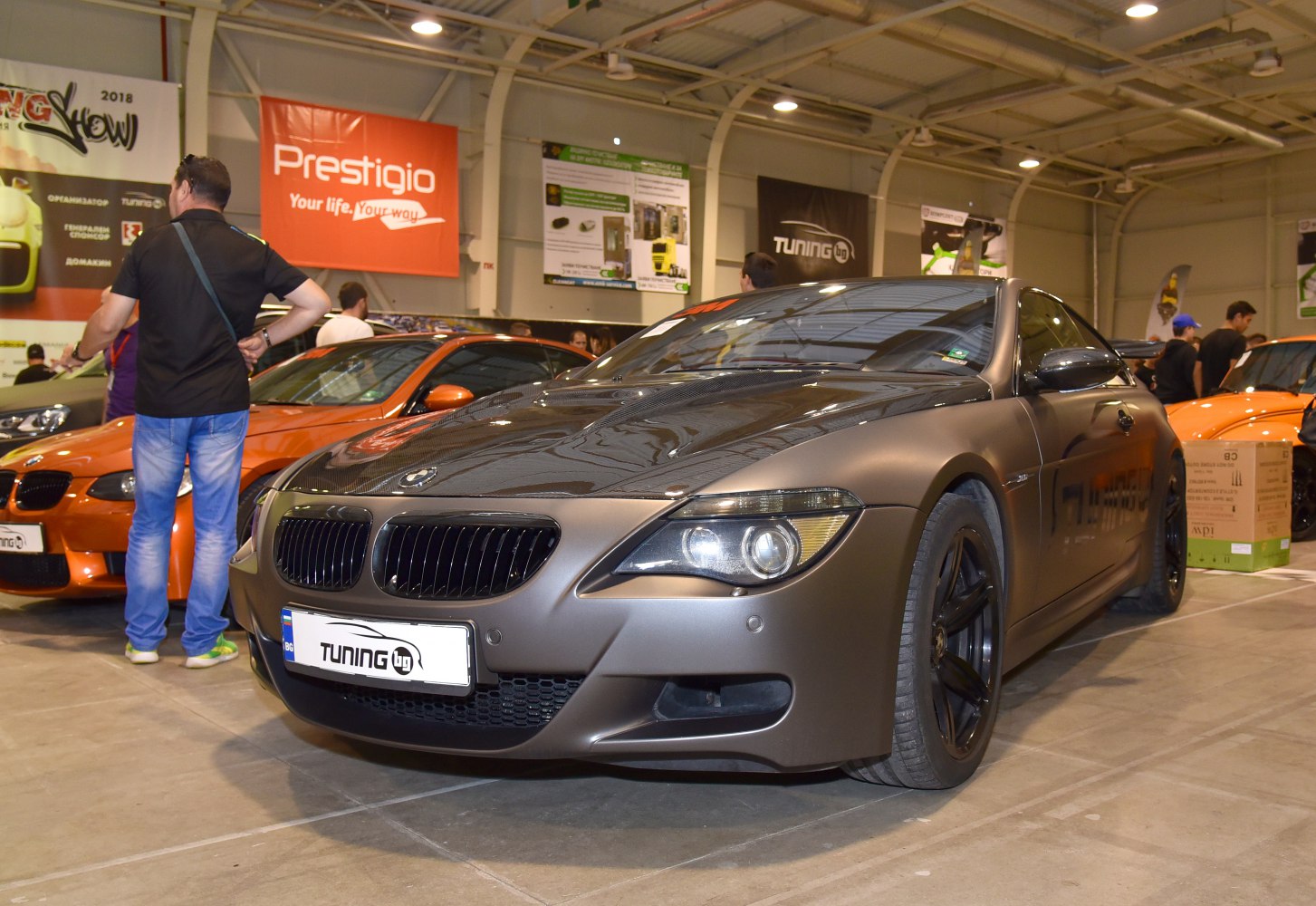 Matte black BMW coupe with carbon fiber hood and black rims