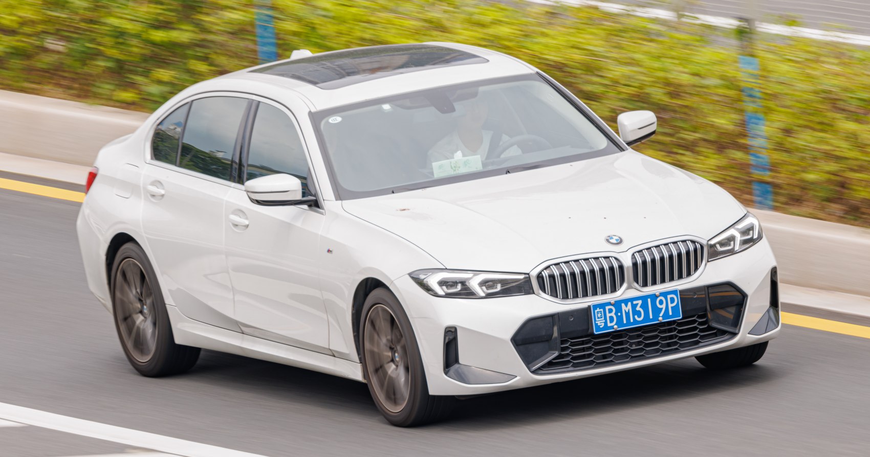 Dynamic front-side view of white luxury sedan with distinctive headlights and kidney grille